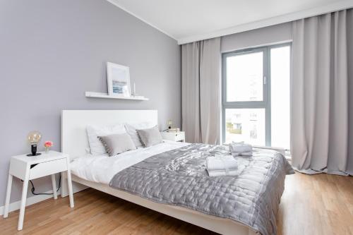 a white bedroom with a large bed and a window at Seaside Beach 150m do Plaży - Praia Apartments - Polsat Plus Arena in Gdańsk