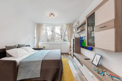 a bedroom with a bed and a tv on a wall at Ada Bucharest Apartment in Bucharest