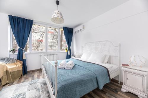 um quarto branco com uma cama com um cobertor azul em Ada Bucharest Apartment em Bucareste