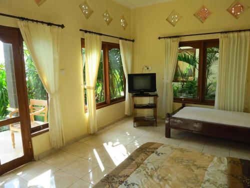 a bedroom with a bed and a tv and windows at Anugerah Villas in Amed