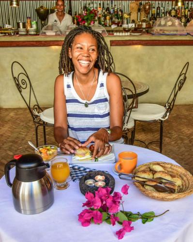 a woman sitting at a table with a plate of food at The Colonial Guest House in São Filipe