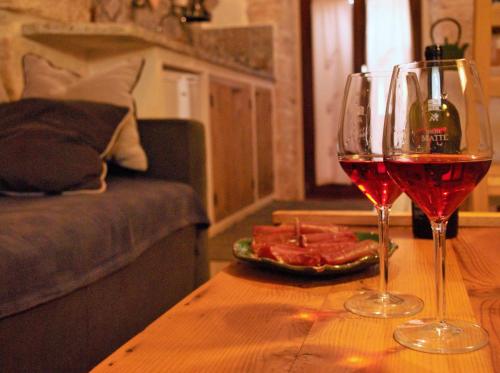 een tafel met twee glazen wijn en een bord vlees bij B&B Trulli Mansio in Alberobello