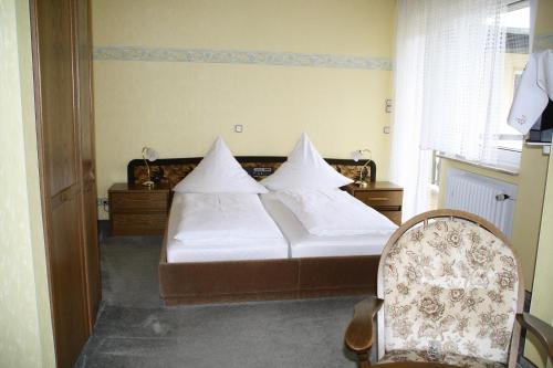 a bedroom with a bed with white sheets and a chair at Haus Klosterblick in Kröv