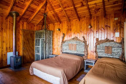 a bedroom with two beds in a wooden cabin at Apart hotel Puchaley Lafquen in Panguipulli