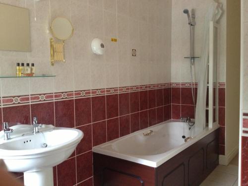 een badkamer met een bad, een wastafel en een bad bij Lyons Woodlands Hall in Ruthin