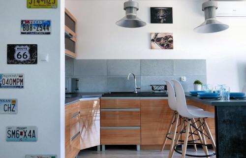 a kitchen with a sink and a counter with white chairs at CHILLIapartamenty - Navigator - MUSTANG in Kołobrzeg