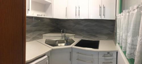 a small kitchen with white cabinets and a sink at Apartment NECA in Lovište
