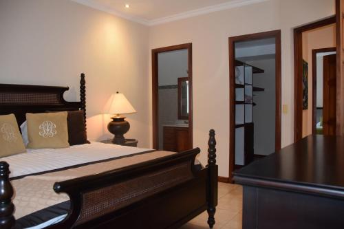 a bedroom with a bed and a table with a lamp at Palm Coast Luxury Rentals in Esterillos Este