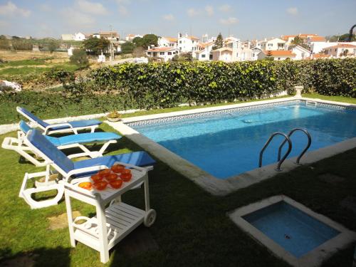 a chair and a table next to a swimming pool at Villa São Filipe in Baleia