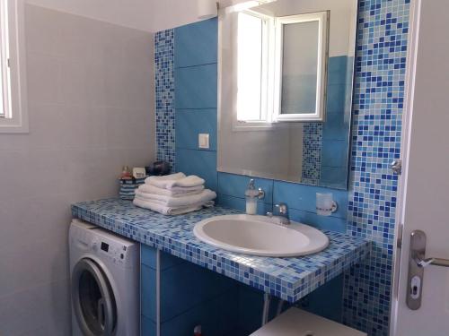 a bathroom with a sink and a washing machine at Acharavi, villa next to the beach in Acharavi