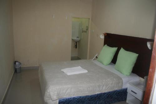 a bedroom with a large bed with green pillows at Honeybed Lodge in Lusaka