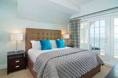 a bedroom with a large bed with blue pillows at Water's Edge Resort & Spa in Westbrook