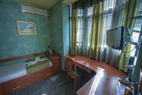 Habitación pequeña con escritorio y TV. en Hotel Kerber en Podgorica