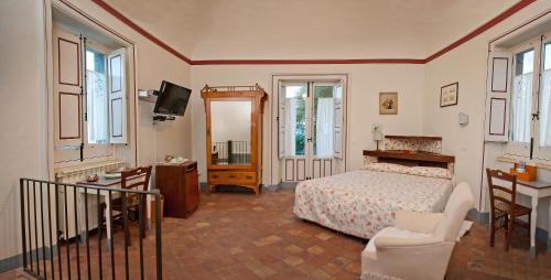 um quarto com uma cama, uma cadeira e uma televisão em Case Perrotta em SantʼAlfio