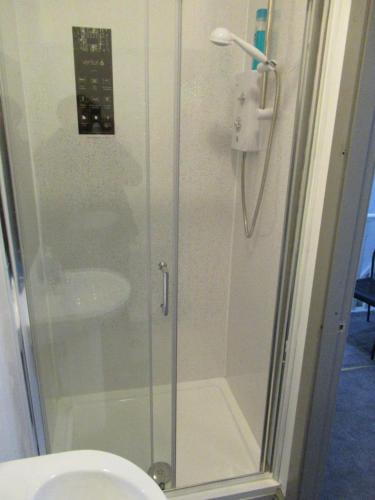een douche met een glazen deur naast een toilet bij Villa Anson in Manchester