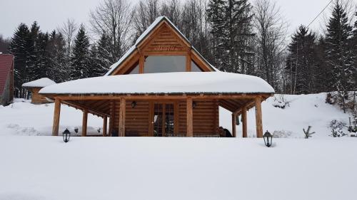 a log cabin with snow on the roof at Vila Maja in Rudno