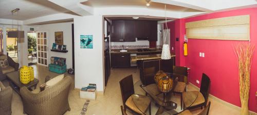 a kitchen with a red wall and some chairs at Summer House Inn San Andres in San Andrés