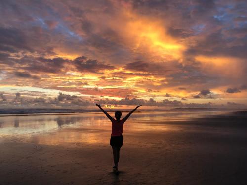 a woman standing on a beach with her arms outstretched at Palm Coast Luxury Rentals in Esterillos Este