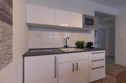 a kitchen with white cabinets and a sink at Standard Apartment by Hi5 - Madách in Budapest