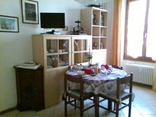 um quarto com uma mesa com cadeiras e uma televisão em A Casa Di Nonna em Tirano