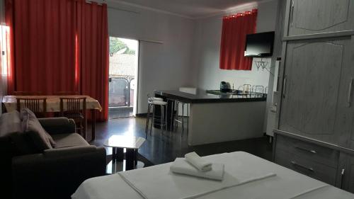 een woonkamer met een bank en een keuken met rode gordijnen bij Hotel Roma in Edéia
