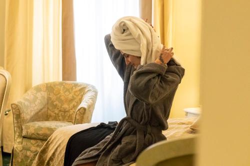 a woman with a turban on her head sitting on a bed at Hotel La Locanda in Volterra