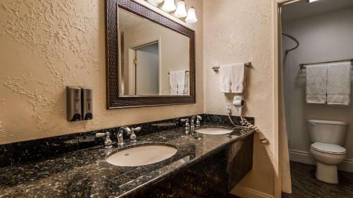 ein Badezimmer mit zwei Waschbecken, einem Spiegel und einem WC in der Unterkunft SureStay Plus Hotel by Best Western Susanville in Susanville