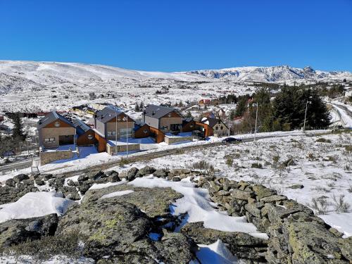 a village in the snow with houses and rocks at Estrela da Serra - Alojamento Local in Penhas da Saúde