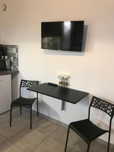 a black table with two chairs and a television on a wall at LE MONICA in Narbonne