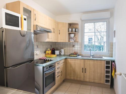 une cuisine avec des armoires en bois et un réfrigérateur en acier inoxydable dans l'établissement Family Travel Paris 2, à Bussy-Saint-Georges