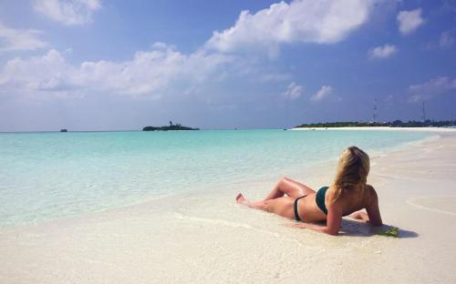 a woman laying on a beach in the ocean at Beach Cottage in Rasdu