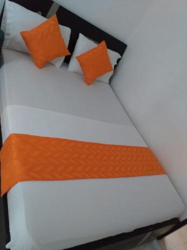 a bed with orange and white pillows on it at Hotel Torres del Parque No3 in Barranquilla