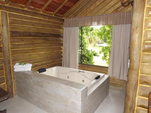 a large bath tub in a room with a window at Hotel Vivenda Penedo in Penedo