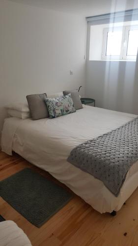 a large white bed with pillows on top of it at Carmo Apartment in Espinho