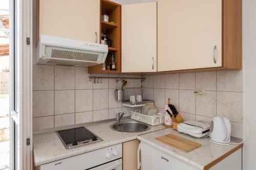 a kitchen with white cabinets and a sink at Eco Apartments Kate in Suđurađ