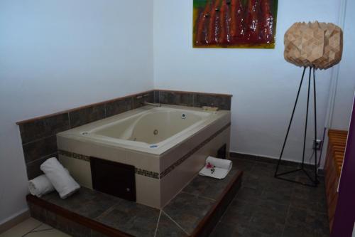 a bath room with a tub, sink and a painting on the wall at Boutique Pueblo Lindo in Taxco de Alarcón