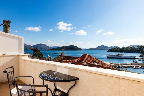 a table and chairs on a balcony with a view of the water at Eco Apartments Kate in Suđurađ