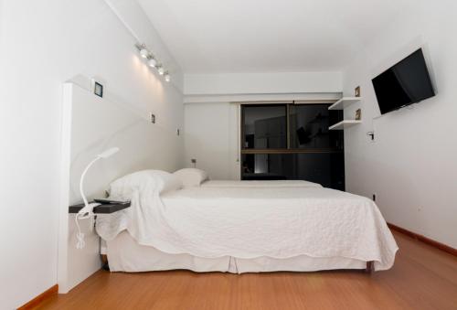 a white bedroom with a bed and a television at Apartamento Torre Cristal in Punta del Este