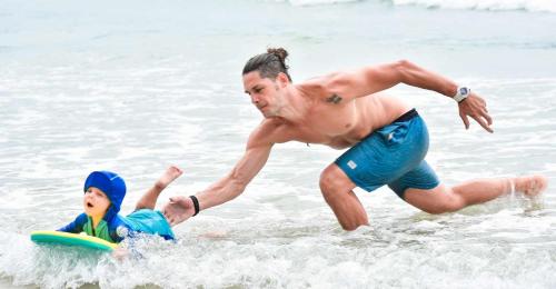 a man and a boy playing in the water at the beach at Hiriketiya Beach Resort in Hiriketiya