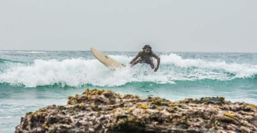 a man riding a wave on a surfboard in the ocean at Hiriketiya Beach Resort in Hiriketiya