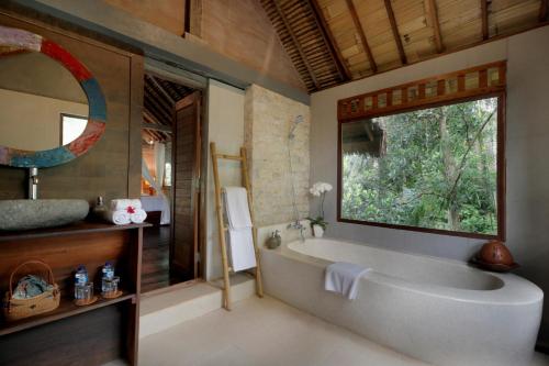 克拉玛斯Keramas Sacred River Retreat Resort and Villa的带浴缸的浴室和窗户。