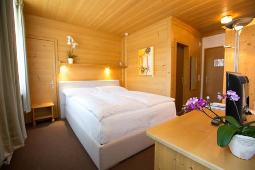 a bedroom with a white bed and a desk at Sonnegg Hotel in Zweisimmen