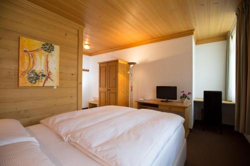a bedroom with a bed and a desk with a computer at Sonnegg Hotel in Zweisimmen