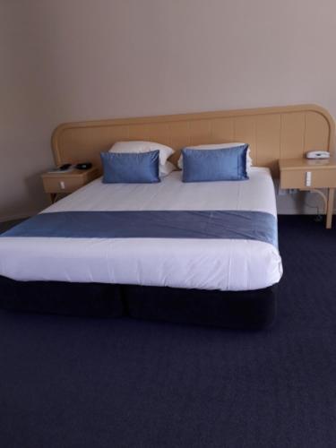 a bedroom with a large bed with blue pillows at Village Motel in Havelock North