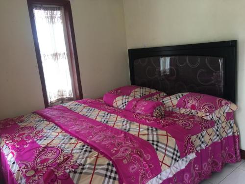 a bed with a pink comforter and pillows at Bromo Deddy Homestay in Bromo