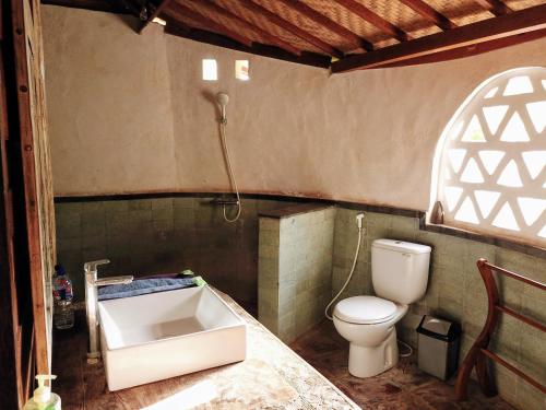 a bathroom with a sink and a toilet at Rhipidura Bungalows by Phocéa in Pemuteran