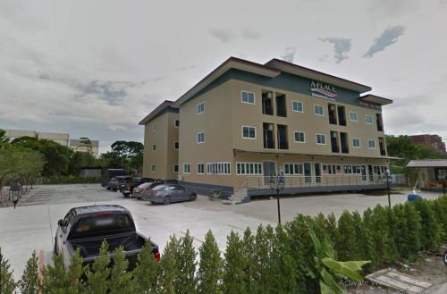 a large building with cars parked in a parking lot at A-Place Suvarnabhumi in Lat Krabang
