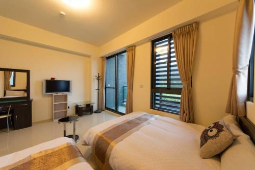a bedroom with two beds and a tv and windows at 七號會館 in Puli