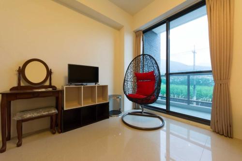 a living room with a red chair and a window at 七號會館 in Puli