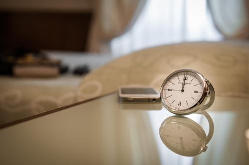 a clock on a table next to a bed at Grand Hotel Bastiani in Grosseto